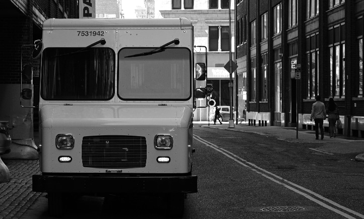 Black and white photograph of a delivery truck parked on a city street